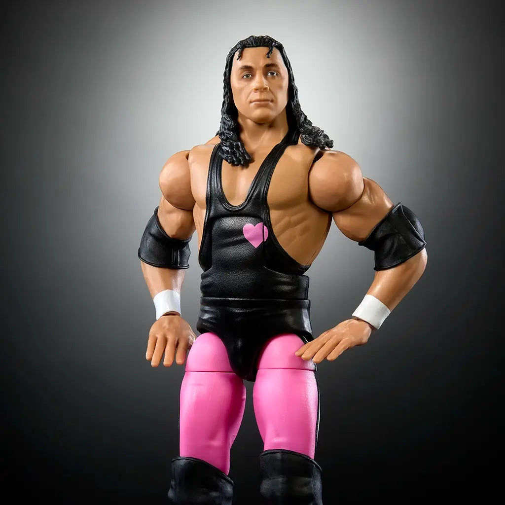 Close-up of WWE Bret Hart Elite Collection figure in black singlet with pink heart design, pink tights, and detailed facial sculpt with long textured hair.