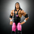 Close-up of WWE Bret Hart Elite Collection figure in black singlet with pink heart design, pink tights, and detailed facial sculpt with long textured hair.