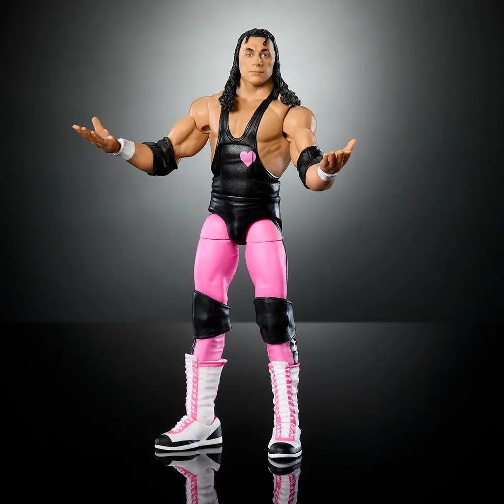 WWE Elite Bret Hart action figure posed with arms open, showcasing deluxe articulation, muscular build, and iconic black and pink wrestling attire.