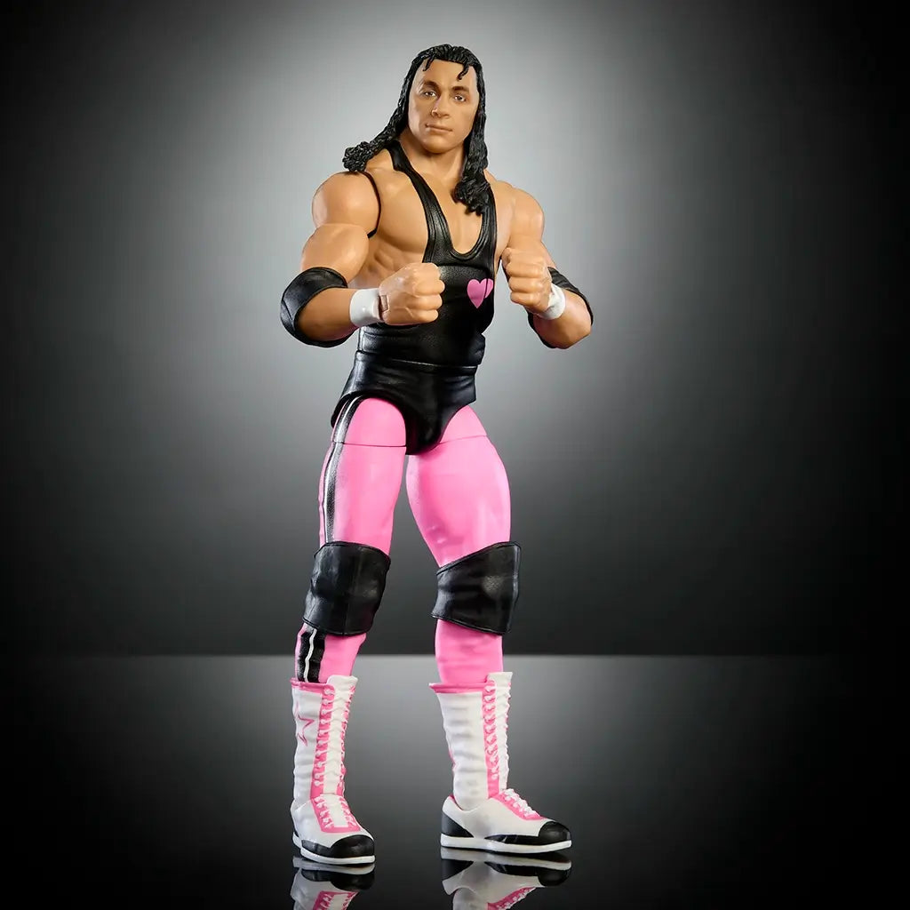 Full front view of WWE Elite Bret Hart action figure in black singlet, pink pants, black kneepads, and tall white lace-up boots with pink accents.