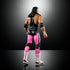 Rear angled view of WWE Elite Bret Hart action figure highlighting detailed hair sculpt, black singlet back, pink tights with side stripes, and tall white boots.