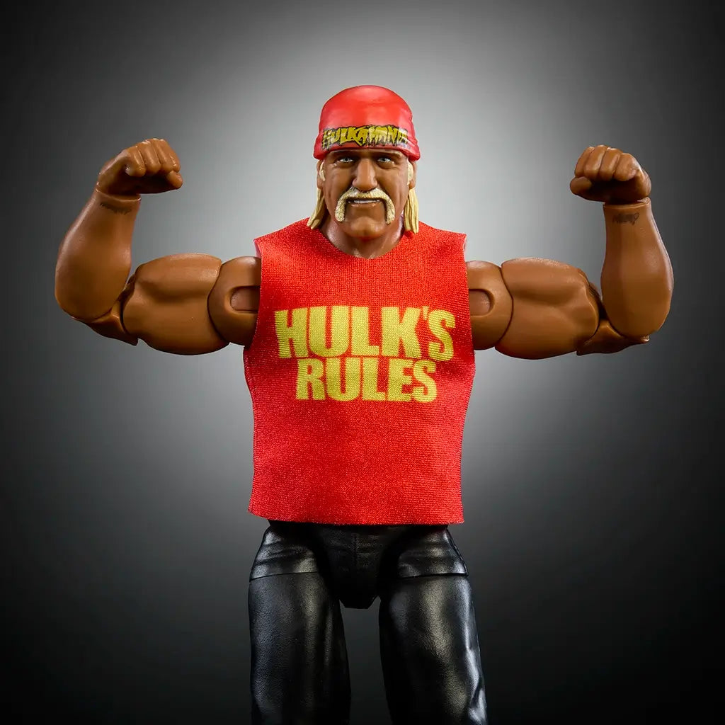 Close-up of Hulk Hogan WWE action figure flexing muscles in red Hulk’s Rules shirt, black pants, red bandana, showing sculpted arms, mustache, and poseable articulation details.