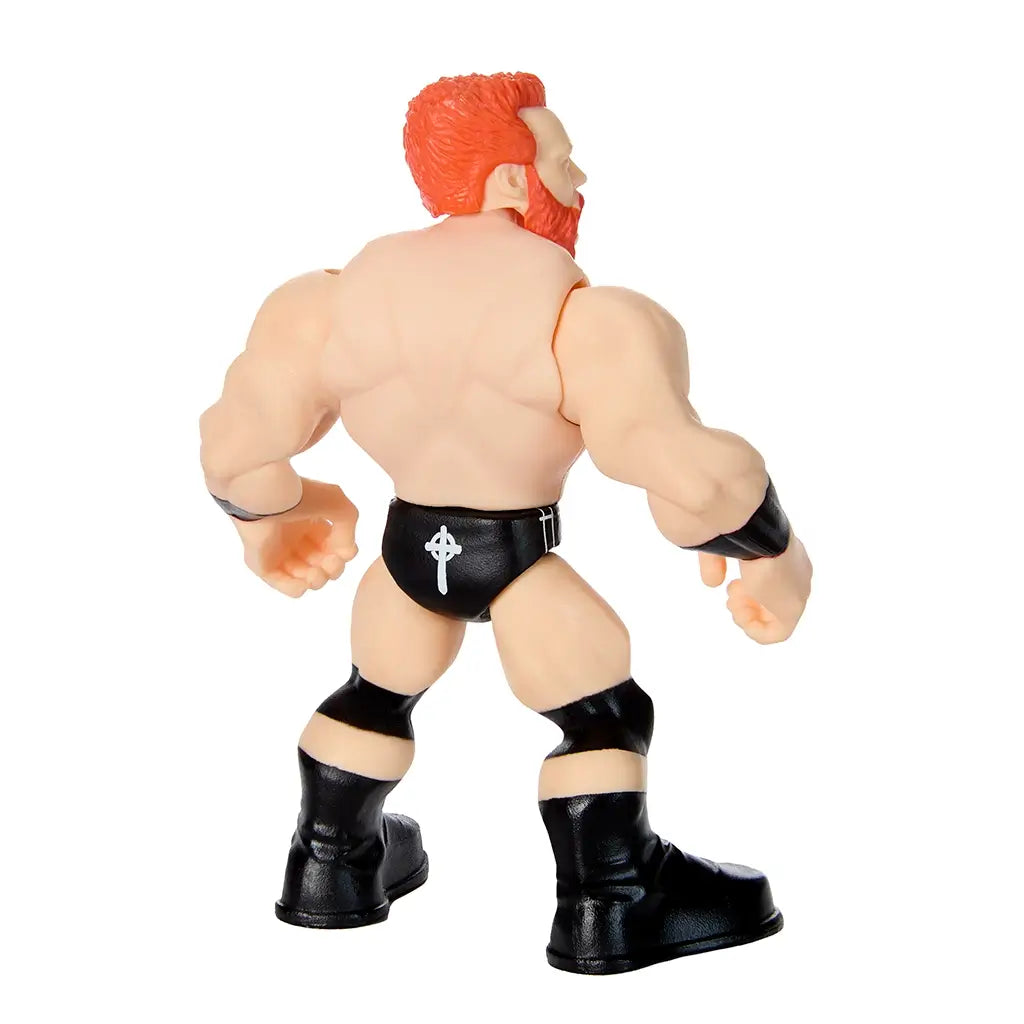 Rear angled view of WWE Sheamus Knuckle Crunchers figure showing muscular back, red hair, black trunks with white Celtic cross design, wristbands, and tall black boots.