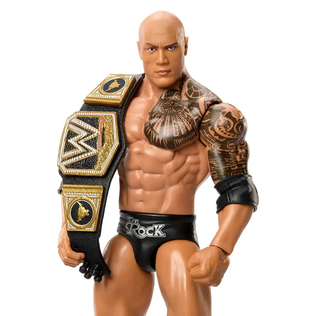 Close-up of The Rock WWE action figure with a gold-outlined championship belt over his shoulder, highlighting intricate tribal tattoo detailing, defined torso sculpting, and molded facial features in bright studio light.