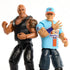 Close-up of WWE Main Event Showdown figures of The Rock in black gear with tattoos and John Cena in blue 'Never Give Up' shirt, posed side by side in wrestling stances.