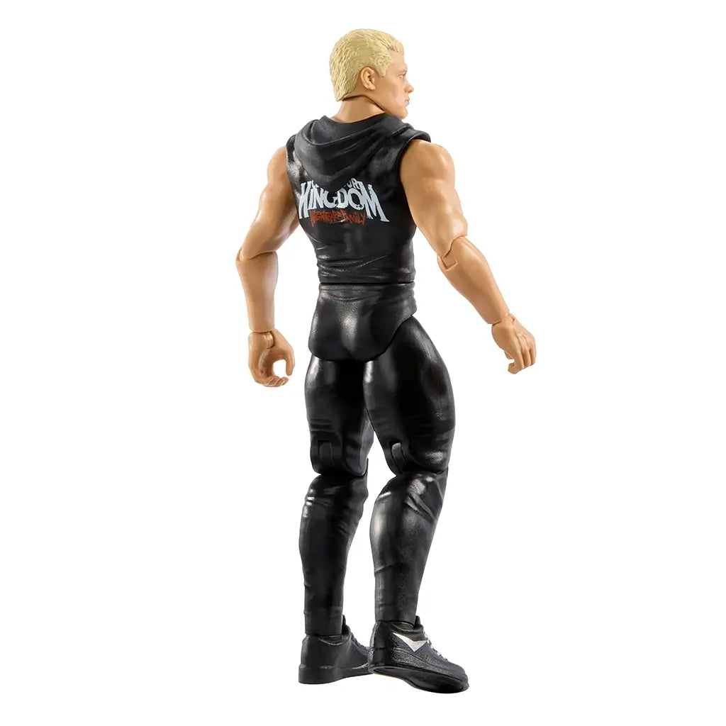 Rear angled view of WWE Cody Rhodes figure in black outfit, showing hooded vest with “Kingdom” text on the back, muscular arms, and detailed sculpting of hair and shoes.