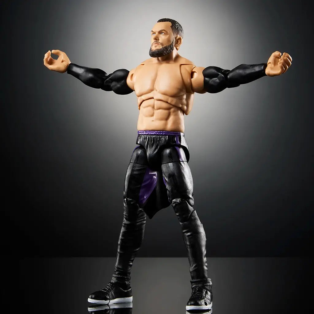 Articulated WWE Finn Bálor Ultimate Edition figure posed with arms wide open, showing muscular sculpt, detailed black pants with purple stripe, and black sneakers on display base.