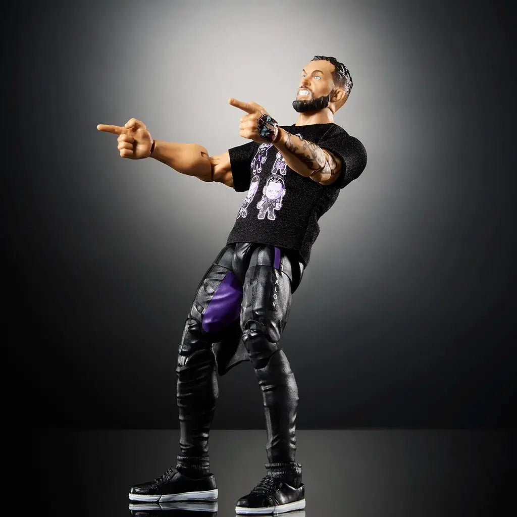 WWE Finn Bálor Ultimate Edition figure striking a pose, dressed in black pants and a printed Judgment Day t-shirt, pointing with detailed tattooed arms and expressive face sculpt.