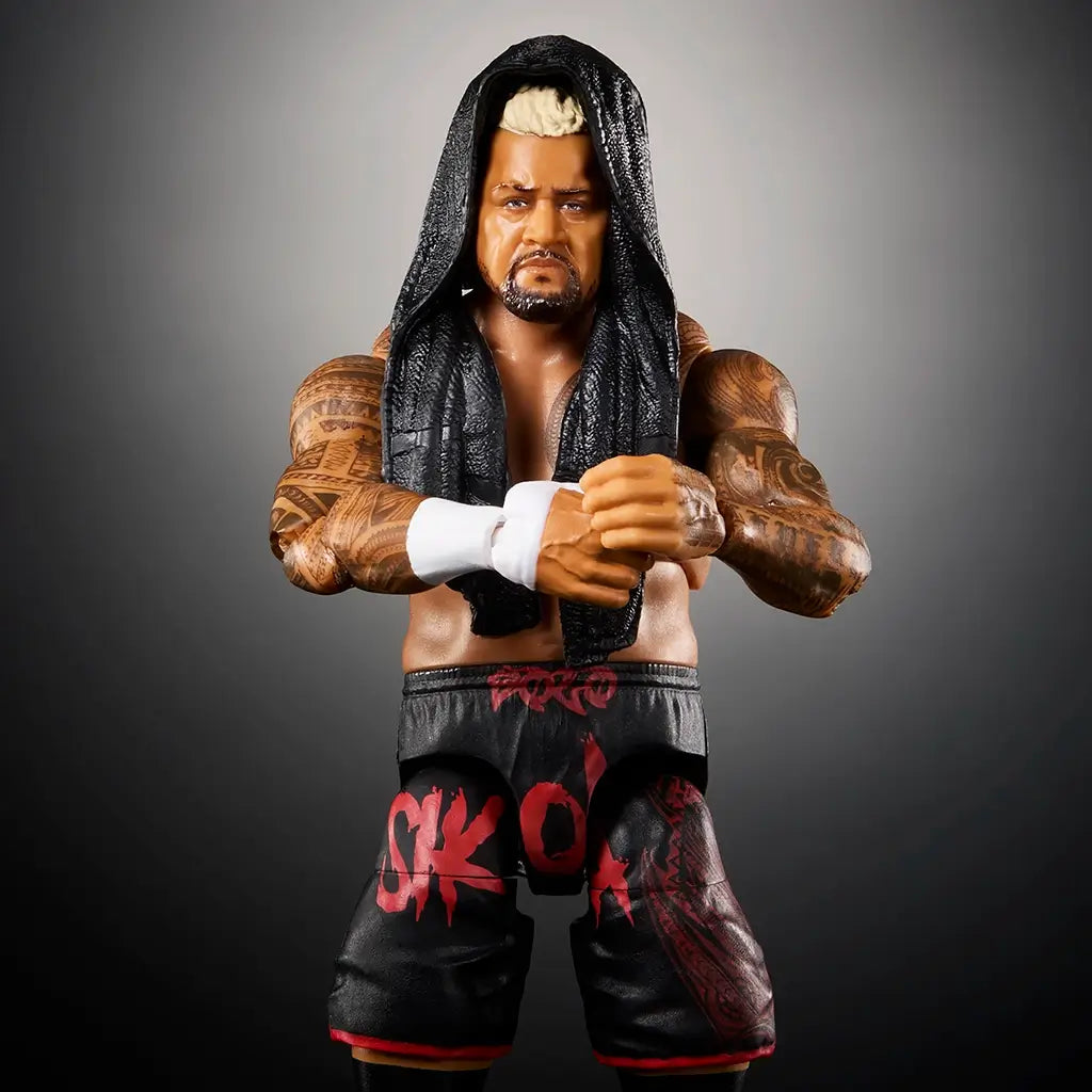 WWE Solo Sikoa action figure close-up with detailed tattoos, black hooded vest, black shorts with red graphics, and white wrist tape against a dark gradient background.