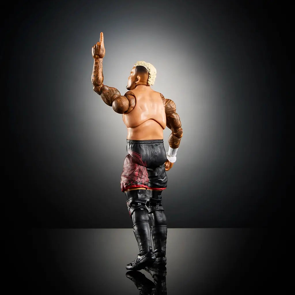 WWE Solo Sikoa action figure rear angle showing muscular build, tattooed arms, black shorts with red tribal graphics, and one finger raised in victory pose on reflective surface.