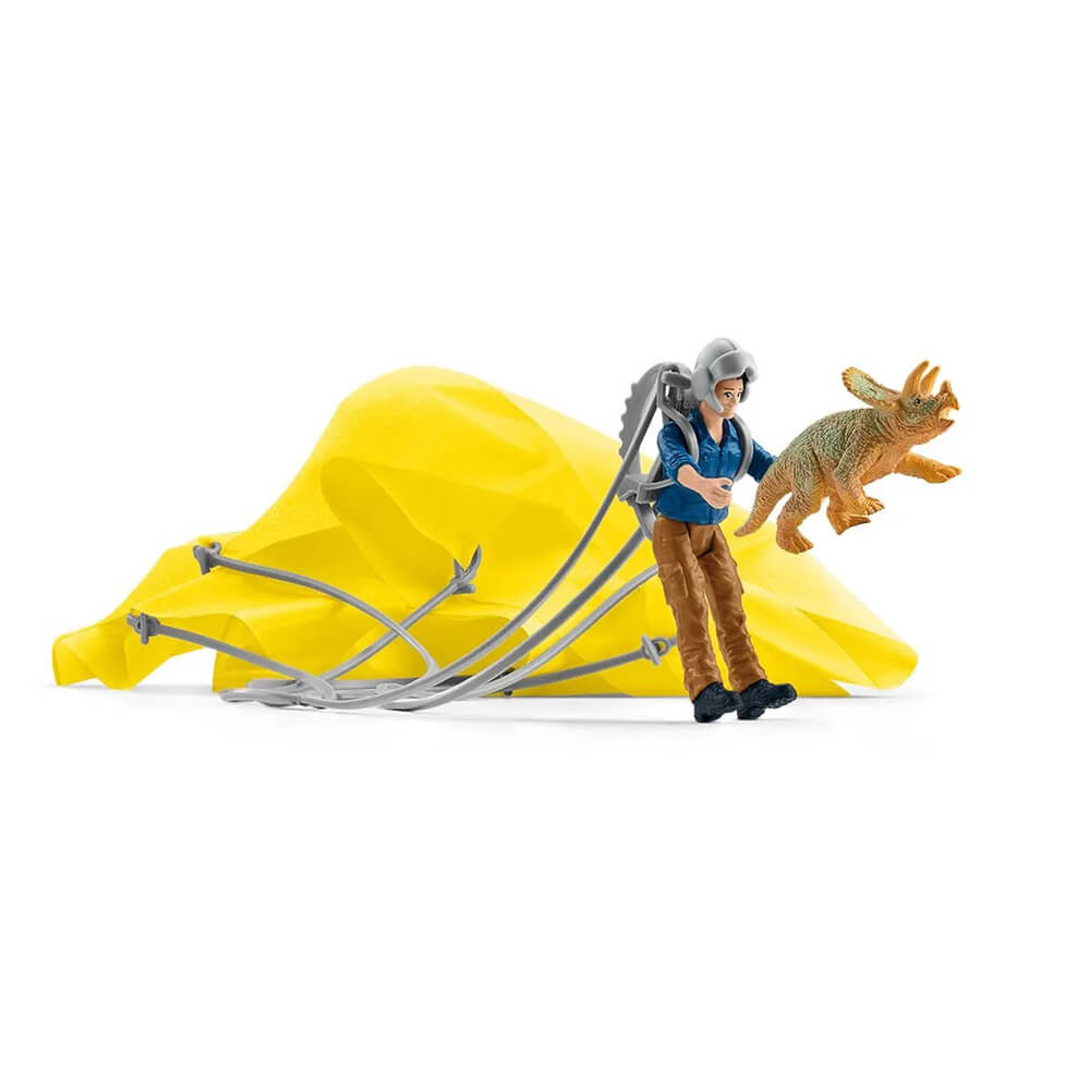 Yellow Schleich Dinosaurs Parachute Rescue set features a collapsed fabric canopy and gray cords beside a blue-shirted explorer holding a small horned dinosaur on a white background.